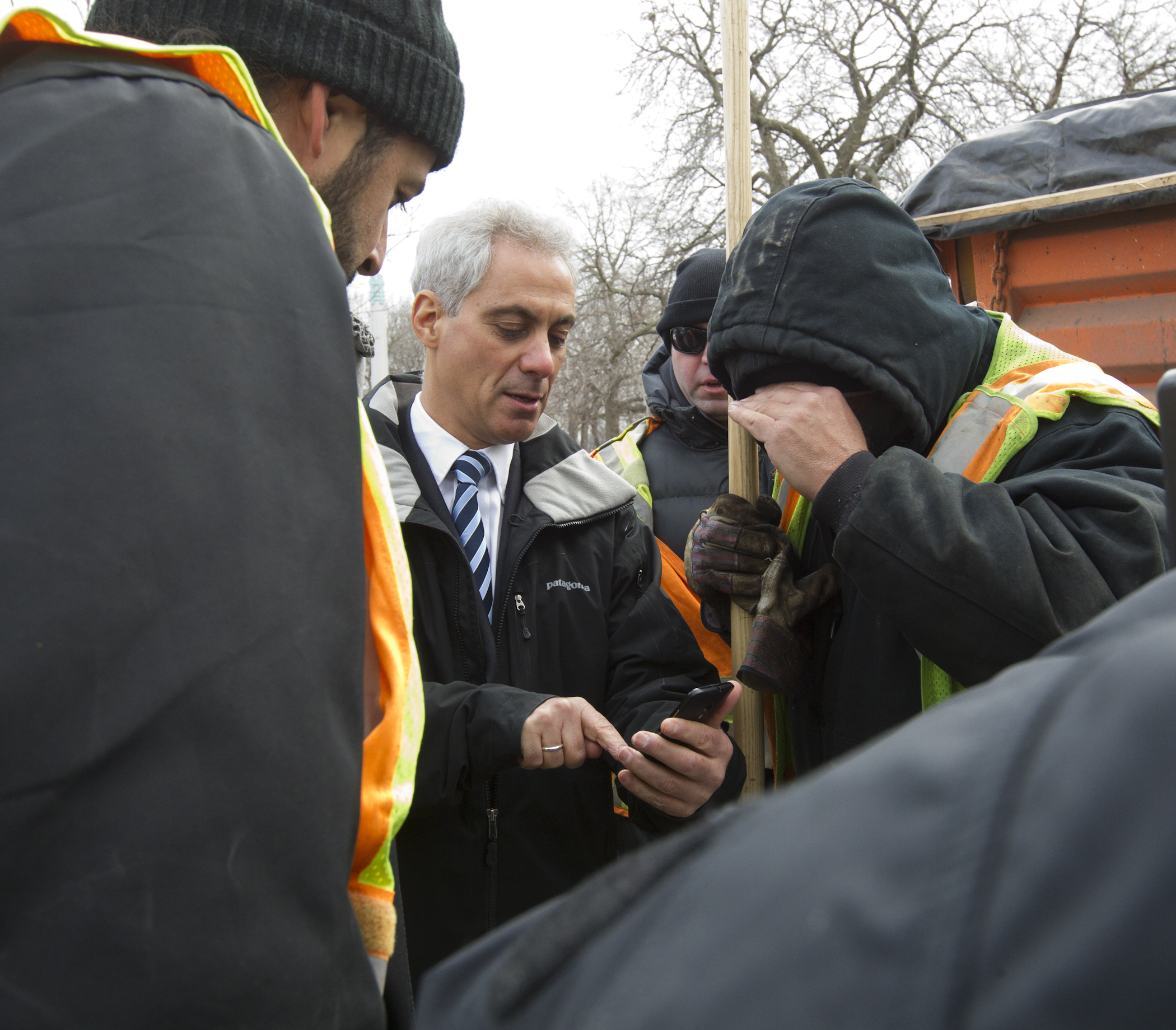 Mayor Rahm Emanuel uses his smartphone to demonstrate the new Pothole Tracker during a stop to thank CDOT crews filling potholes on North Marine Drive.